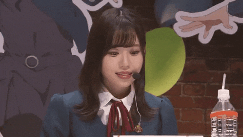 a young woman wearing a blue jacket and a red bow tie is wearing a microphone .