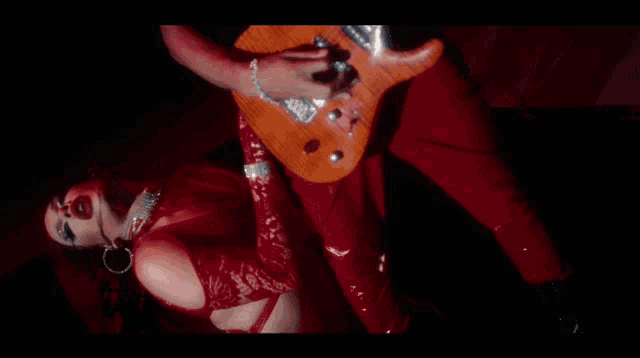 a woman in red holds a guitar in her hand
