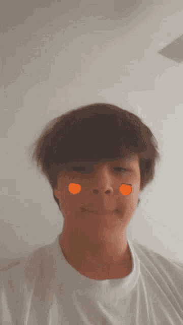 a young man wearing a white t-shirt has orange stickers on his face