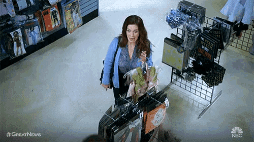 a woman is standing in a store holding a bunch of clothes