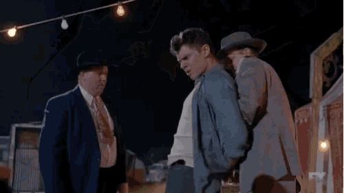 a man in a hat is holding another man in a blue shirt .