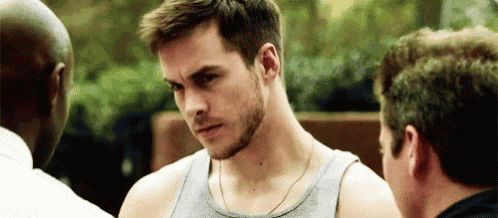 a man with a beard and a tank top is standing in a crowd of people .