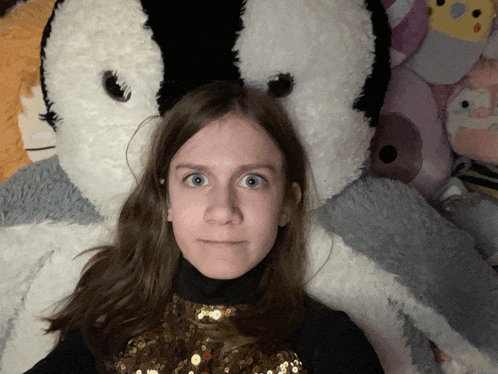 a girl laying on a bed with a stuffed animal behind her