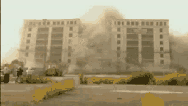 a large building is being demolished and smoke is coming out of the building