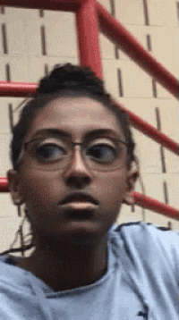 a woman wearing glasses is taking a selfie in front of a red railing