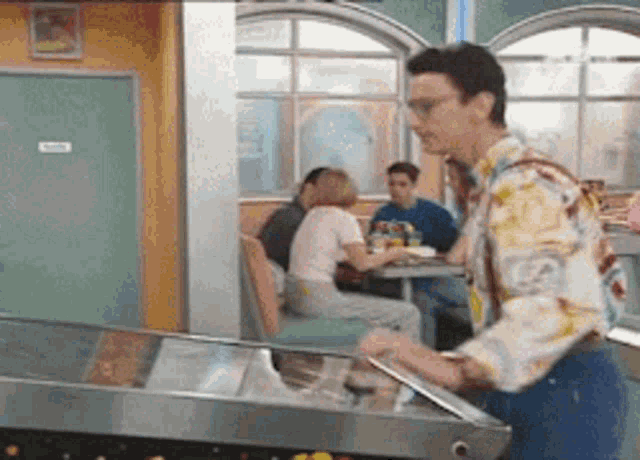 a man is playing pinball in a diner while people sit at tables
