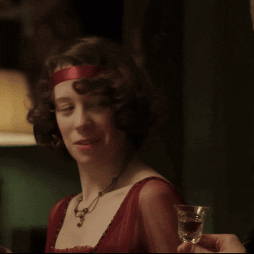 a woman in a red dress smiles while holding a shot glass