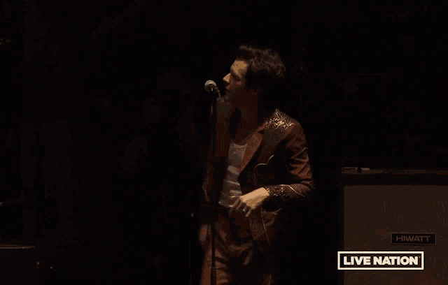 a man in a red suit is singing into a microphone with a live nation logo in the background