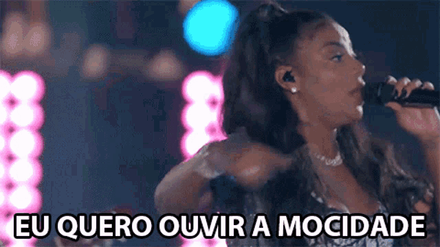a woman singing into a microphone with the words eu quero ouvir a mocidade written below her