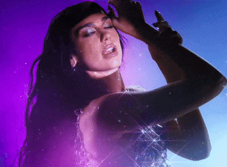 a woman is singing into a microphone in front of a purple and blue background