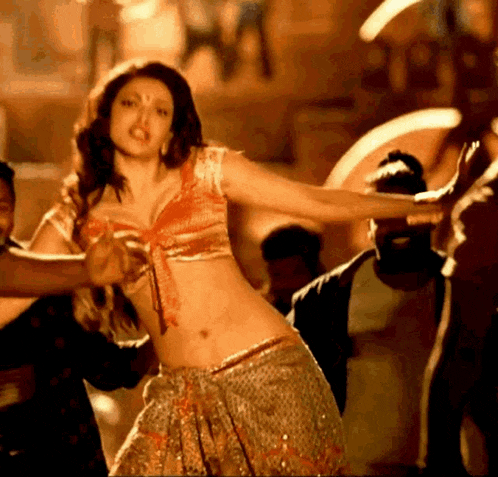 a woman in a crop top and skirt is dancing in a crowd