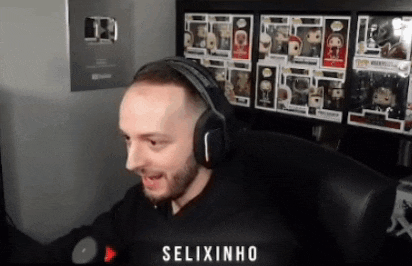 a man wearing headphones is sitting in front of a shelf full of pop figures .