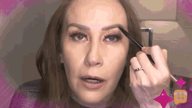 a woman with a ring on her finger applying makeup
