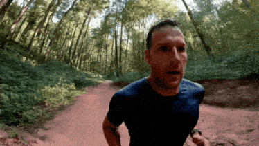 a man in a blue shirt is running through a forest