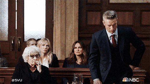 a man in a suit and tie stands in front of a group of people in a courtroom with the nbc logo on the bottom