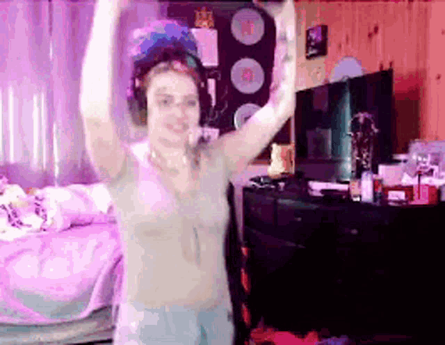 a woman wearing headphones is dancing in front of a tv