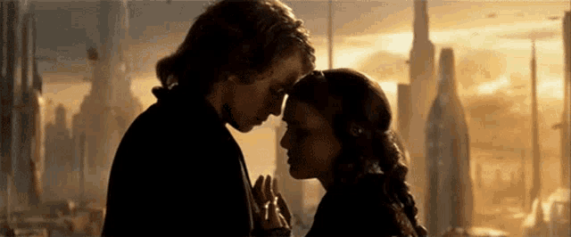 a man and a woman are looking into each other 's eyes in front of a futuristic city .