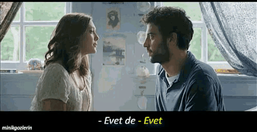 a man and a woman are looking at each other in front of a window with a caption that says evet de evet