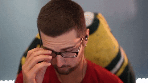 a man wearing glasses and earbuds looks down at something