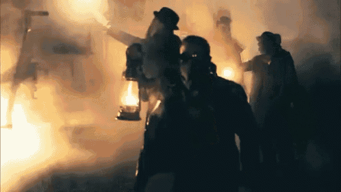 a group of people are walking through a dark room with smoke coming out of the walls .
