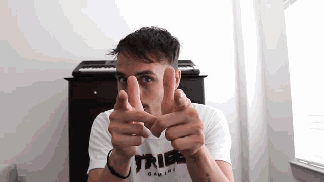 a man wearing a white shirt that says tribe gaming is pointing at the camera