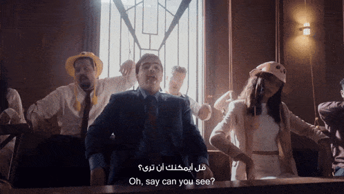 a man in a suit and tie is surrounded by other people and says oh say can you see