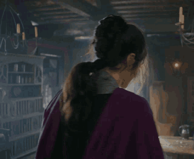 a woman in a purple cape stands in a room