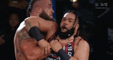 two wrestlers are wrestling in a ring and one of them is holding the other 's neck .