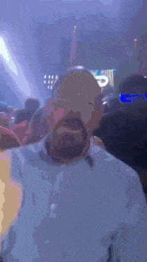 a man with glasses and a beard is standing in a dark room