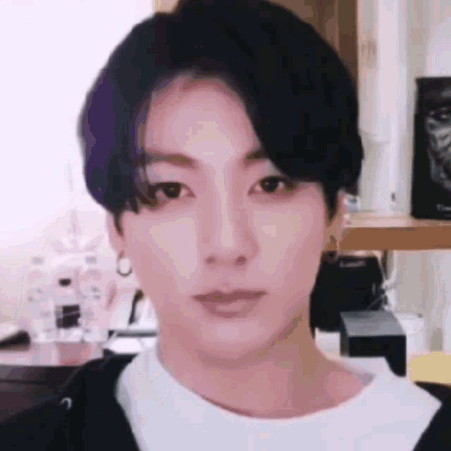 a close up of a person 's face with a black haircut and a white shirt .