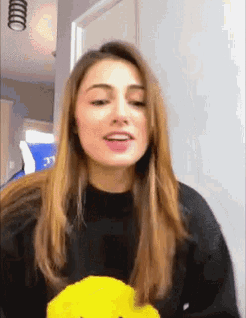 a woman is wearing a black sweater with a yellow smiley face on it .