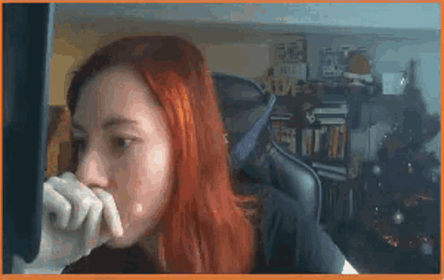 a woman with red hair is sitting in front of a computer monitor .