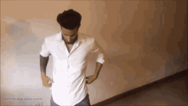 a man in a white shirt is standing in a room