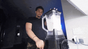 a man in a black shirt is using a blender to blend something