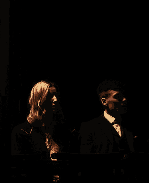 a man and a woman are standing in a dark room