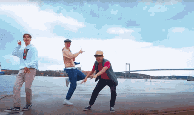 three young men are dancing in front of a bridge