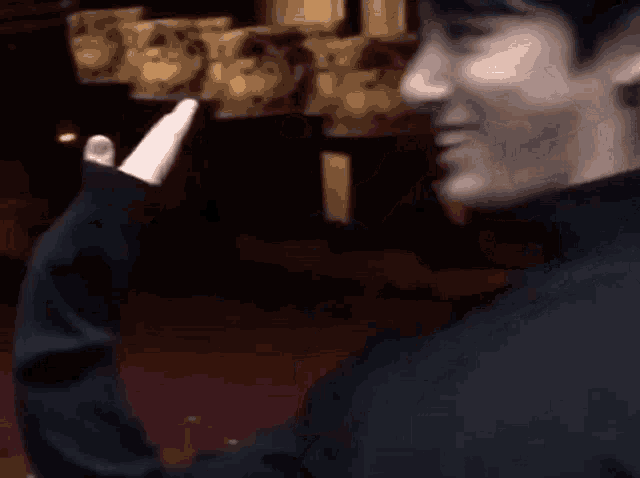 a man in a black turtleneck sweater is waving his hand in the air .