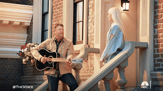 a man playing a guitar next to a woman on stairs