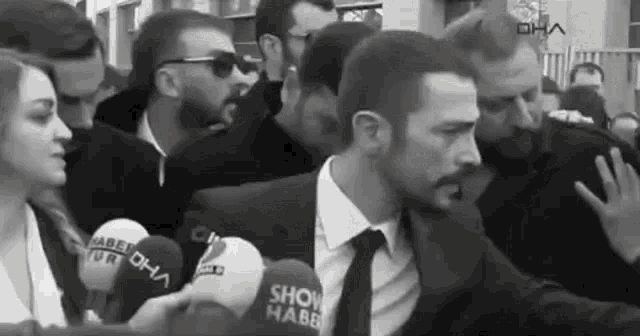 a man in a suit and tie is being interviewed by a group of people in a black and white photo .