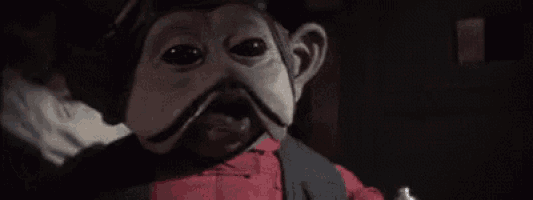 a close up of a puppet with a mustache and a red shirt .