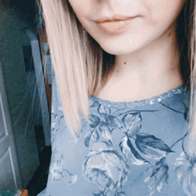 a close up of a woman 's face in a blue floral shirt