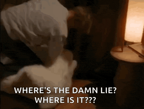 a man is laying on a bed with a pillow and a lamp and says where 's the damn lie ?