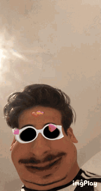 a man wearing sunglasses has hearts on his forehead and the word imgplay is on the bottom right