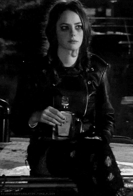 a black and white photo of a woman wearing a leather jacket and holding a lighter .
