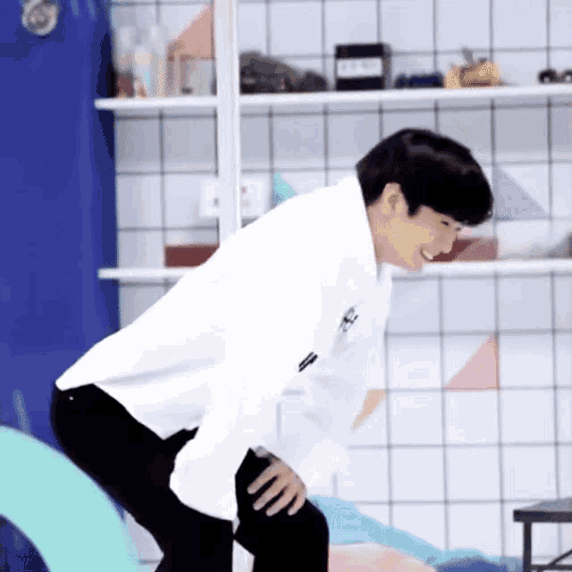 a man in a white shirt is kneeling down and smiling