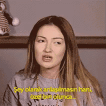 a woman is wearing a gray sweater and talking in a foreign language