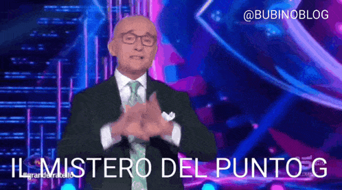 a man in a suit and tie stands on a stage and says il mistero del punto g in sign language