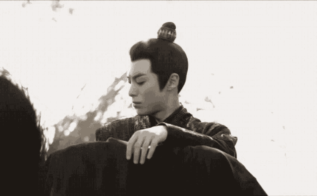 a black and white photo of a man with a bun