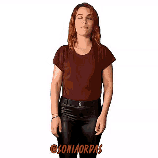a woman wearing a maroon shirt and black pants is making a funny face
