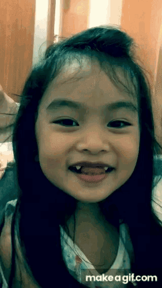 a little girl is making a funny face with makeagif.com in the corner